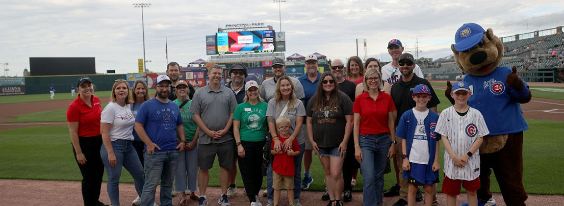 A group of people smiling on a baseball field.